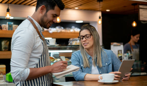 istock Beautiful latin american customer ordering something to waiter while she holds her tablet both smiling 1128053684