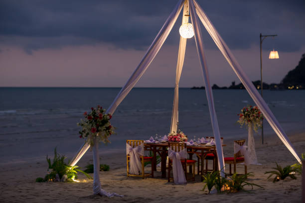 istock Romantic dinning table on the beach . Table setting at a luxury wedding and Beautiful flowers on the table. 1128054354