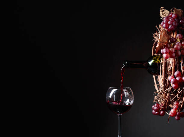 istock Red wine pouring from a bottle into a glass. 1128054627