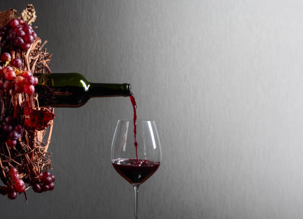 istock Red wine pouring from a bottle into a glass. 1128054631