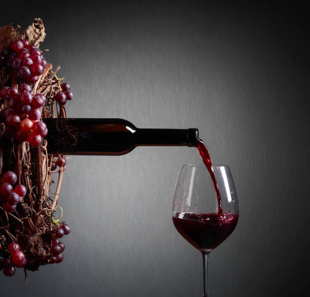 istock Red wine pouring from a bottle into a glass. 1128054632