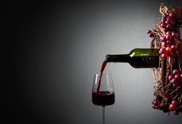 istock Red wine pouring from a bottle into a glass. 1128054633