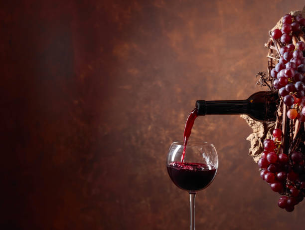 istock Red wine pouring from a bottle into a glass. 1128054634