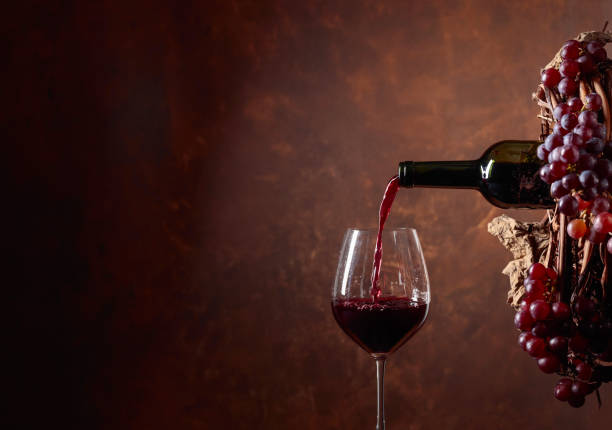 istock Red wine pouring from a bottle into a glass. 1128054637