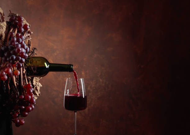 istock Red wine pouring from a bottle into a glass. 1128054640