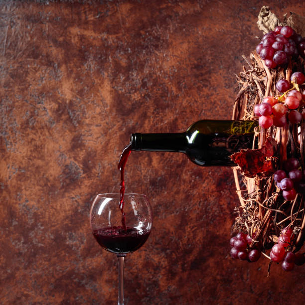 istock Red wine pouring from a bottle into a glass. 1128054644