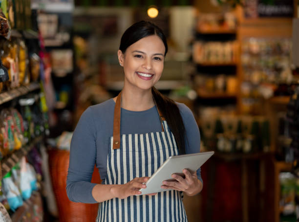 istock Beautiful manager of a grocery store holding tablet while facing camera smiling 1128056223