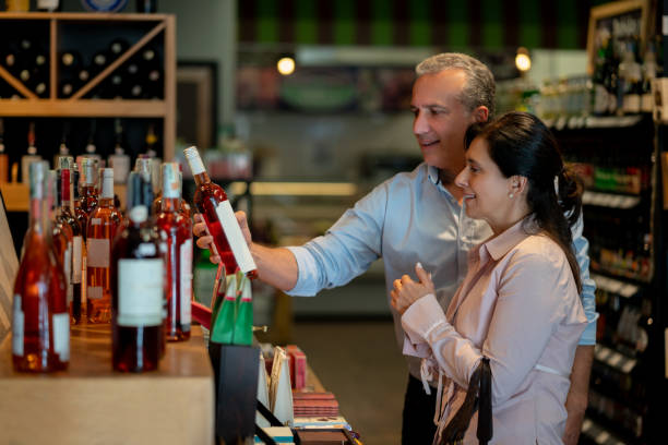 istock Mature couple at a supermarket looking at a rose bottle while talking 1128056230