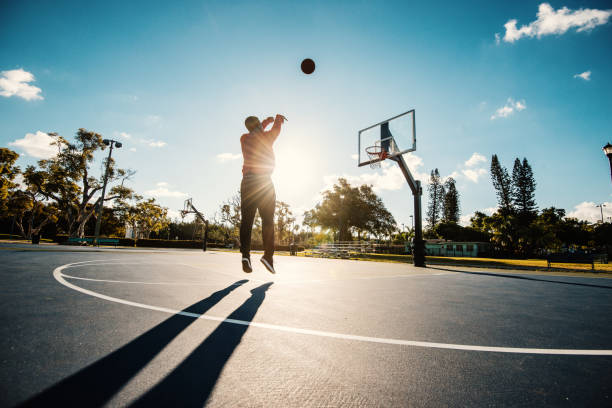 Latino guy shooting basketball on the court in USA in summer Playing basketball for healthy lifestyle in USA making a basket scoring stock pictures, royalty-free photos & images