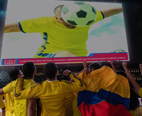 Happy group of Colombian football fans watching the game at a sports bar