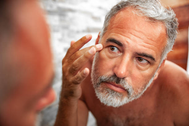 istock Sunburned Mature Man looking into the Mirror in the bathroom 1128066195