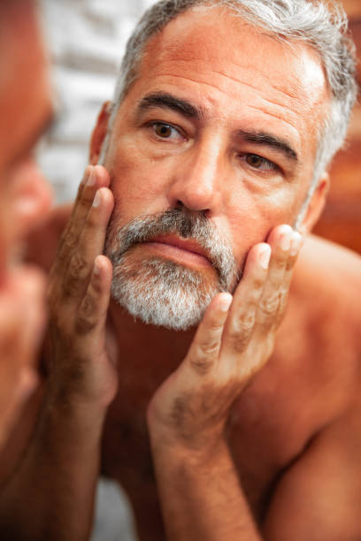istock Sunburned Mature Man looking into the Mirror in the bathroom 1128066198