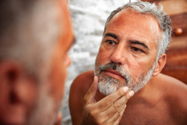 istock Sunburned Mature Man looking into the Mirror in the bathroom 1128066201