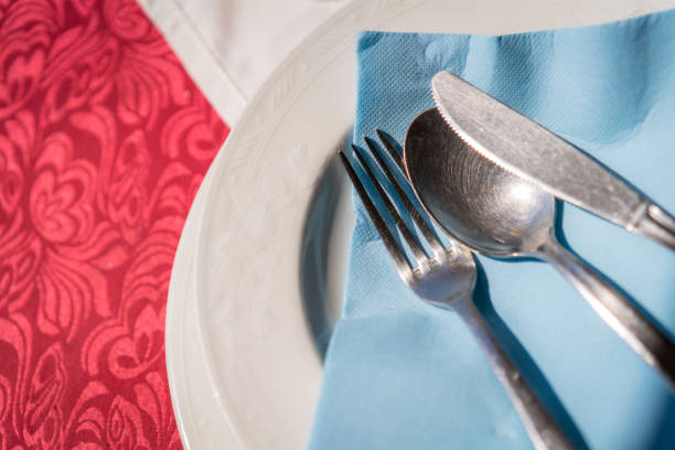 istock Fork, knife and spoon on a blue napkin on a plate 1128070691