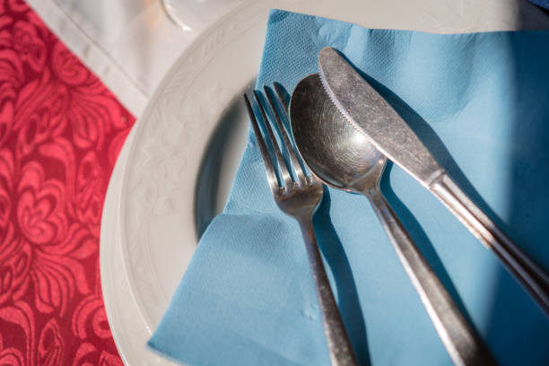 istock Fork, knife and spoon on a blue napkin on a plate 1128070718