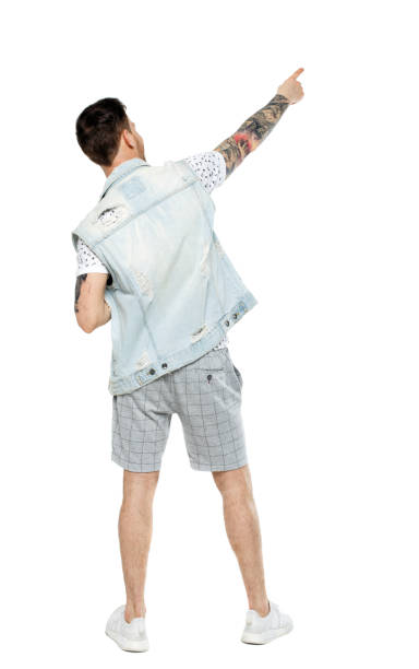 istock Back view of a stylish man iin shorts points his hand upwards. 1128070801