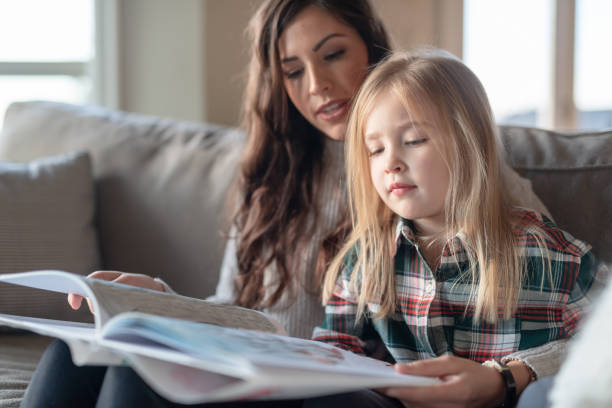 istock Mom reads with her young daughter on the couch 1128073563