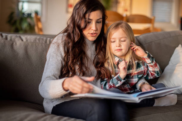 istock Mom reads with her young daughter on the couch 1128073594