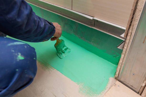 Worker is painting by brush with green colored waterproof finish material the bathroom floor in apartment is inder construction, remodeling, renovation, overhaul, extension, restoration and reconstruction. Concept of home improvement trabajador es la pintura a pincel con verde impermeable color acabado material el piso del baño en apartamento es inder construcción, remodelación, renovación, revisión, ampliación, restauración y reconstrucción. concepto de mejoras para el hogar