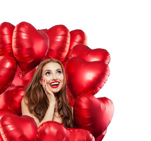 Happy surprised woman with red balloons isolated on white background. Surprised girl with red lips makeup smiling and looking up. Surprise, gifts and Valentine's day concept isolated over white Happy surprised woman with red balloons isolated on white background. Surprised girl with red lips makeup smiling and looking up. Surprise, gifts and Valentine's day concept isolated over white valentine s day holiday stock pictures, royalty-free photos & images