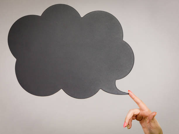 Woman hand pointing at black thinking or speech bubble empty for copyspace or text. Grey background