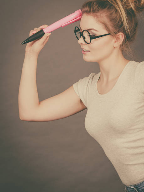 istock Woman holding big oversized pencil thinking about something 1128078047