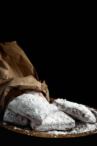 Beignets on Wooden board Beignets on Wooden board from Paper Bag with Powdered Sugar on Black Background beignet stock pictures, royalty-free photos & images