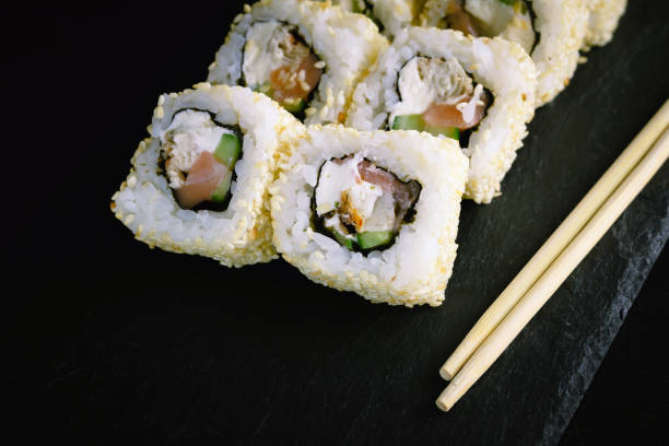 istock Sushi rolls and chopsticks on a black plate. 1128083020