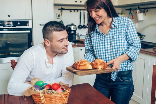 Happy family celebrating Easter with colored eggs and easter bread on table