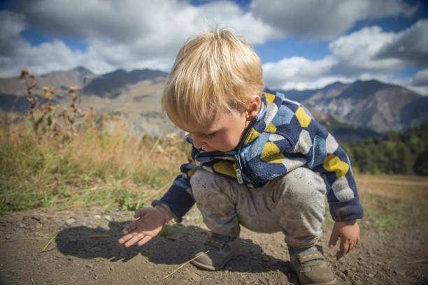Baby boy learning how to walk outside, toddler trying to reach his mother. Baby's first steps.
