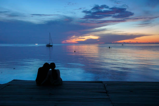 istock Silhouette Friends Sitting Against Sea During Sunset 1128085214