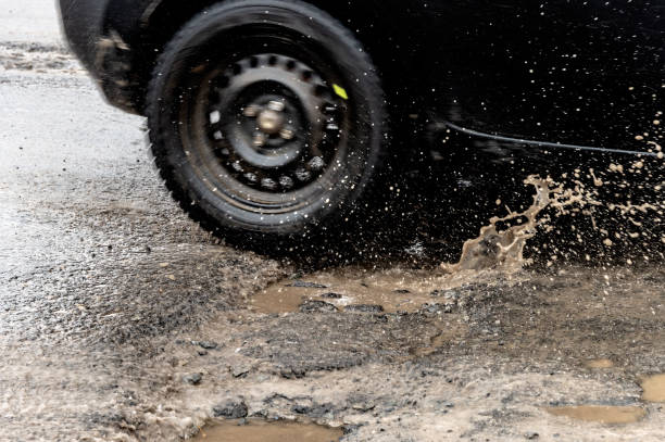 coche atravesando un bache con salpicaduras de agua - road street thoroughfare hole fotografías e imágenes de stock