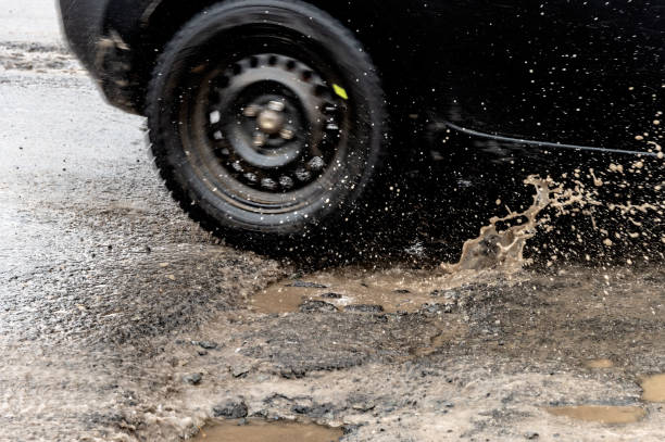 istock Car driving through a pothole with splashes of water 1128085501