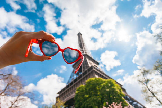 Heart shaped sunglasses in a women hand against Eiffel Tower and blue sky  (Paris France)