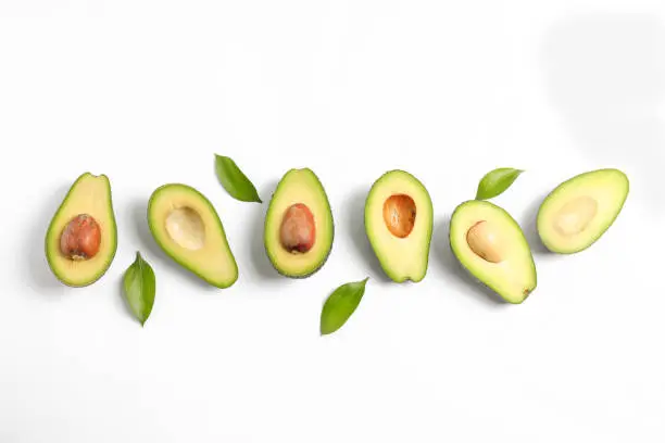 Ripe sliced avocado with green leaves, top view