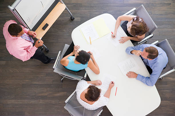 istock Four businesspeople at boardroom table watching presentation 112808734