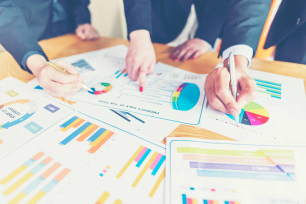 istock Midsection Of Colleagues Analyzing Charts On Office Desk 1128089956