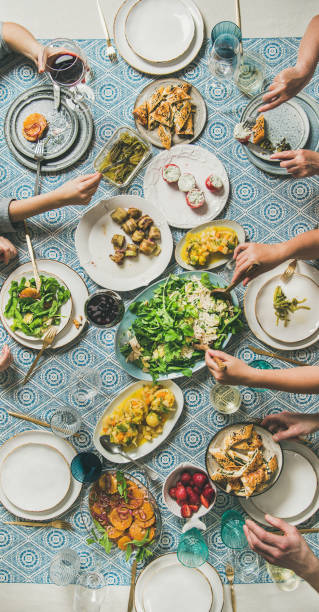 istock Mediterranean style dinner and human hands holding drinks and food 1128090122