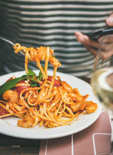 istock Man eating pasta and looking at smartphone 1128090133