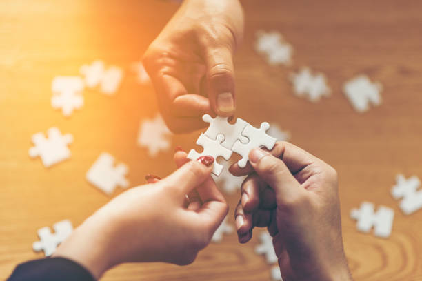 istock Midsection Of Business People Playing With Jigsaw Puzzle On Table 1128092324