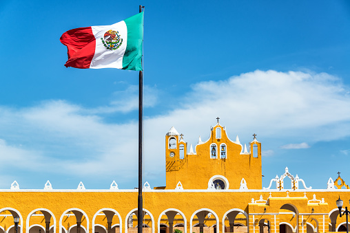 Yellow colonial monastery in Izamal, Mexico with the Mexican flag flying above
