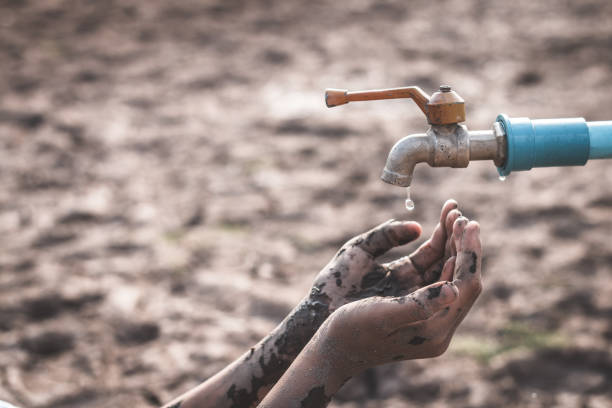 mains sales coupées d’une personne sous le robinet sur une terre stérile pendant la sécheresse - water crisis photos et images de collection
