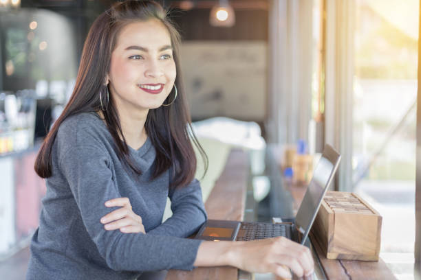 istock Smiling Young Woman Using Laptop While Sitting At Cafe 1128092787