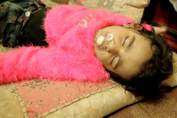 Baby girl sleeping on cushion on floor.