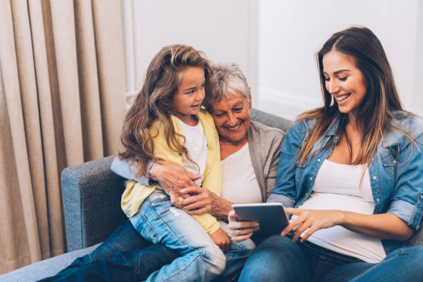 trois femmes de génération sont amuser à la maison - wireless technology cheerful granddaughter grandmother photos et images de collection