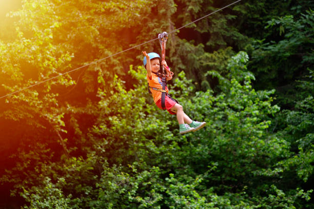 istock Happy kid with helmet and harness on zip line between trees 1128099604