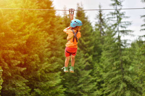 istock Happy kid with helmet and harness on zip line between trees 1128099618