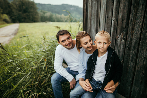 Happy family with son, sitting in front of the barn,enjoying in nature