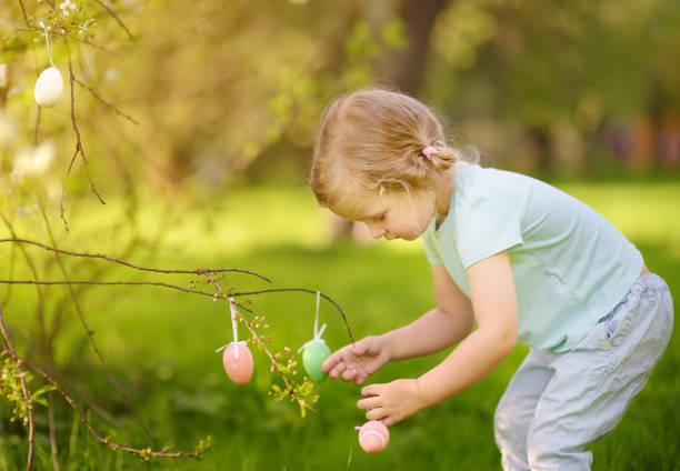 istock Cute little girl hunts for easter egg on branch flowering tree. 1128100646