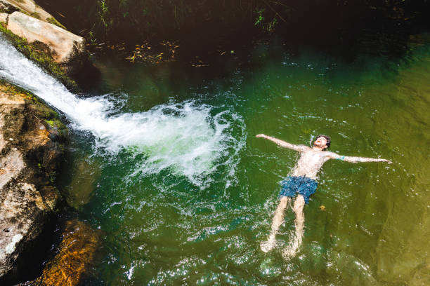 Young man floating on natural pool by a waterfall at Lumiar/RJ